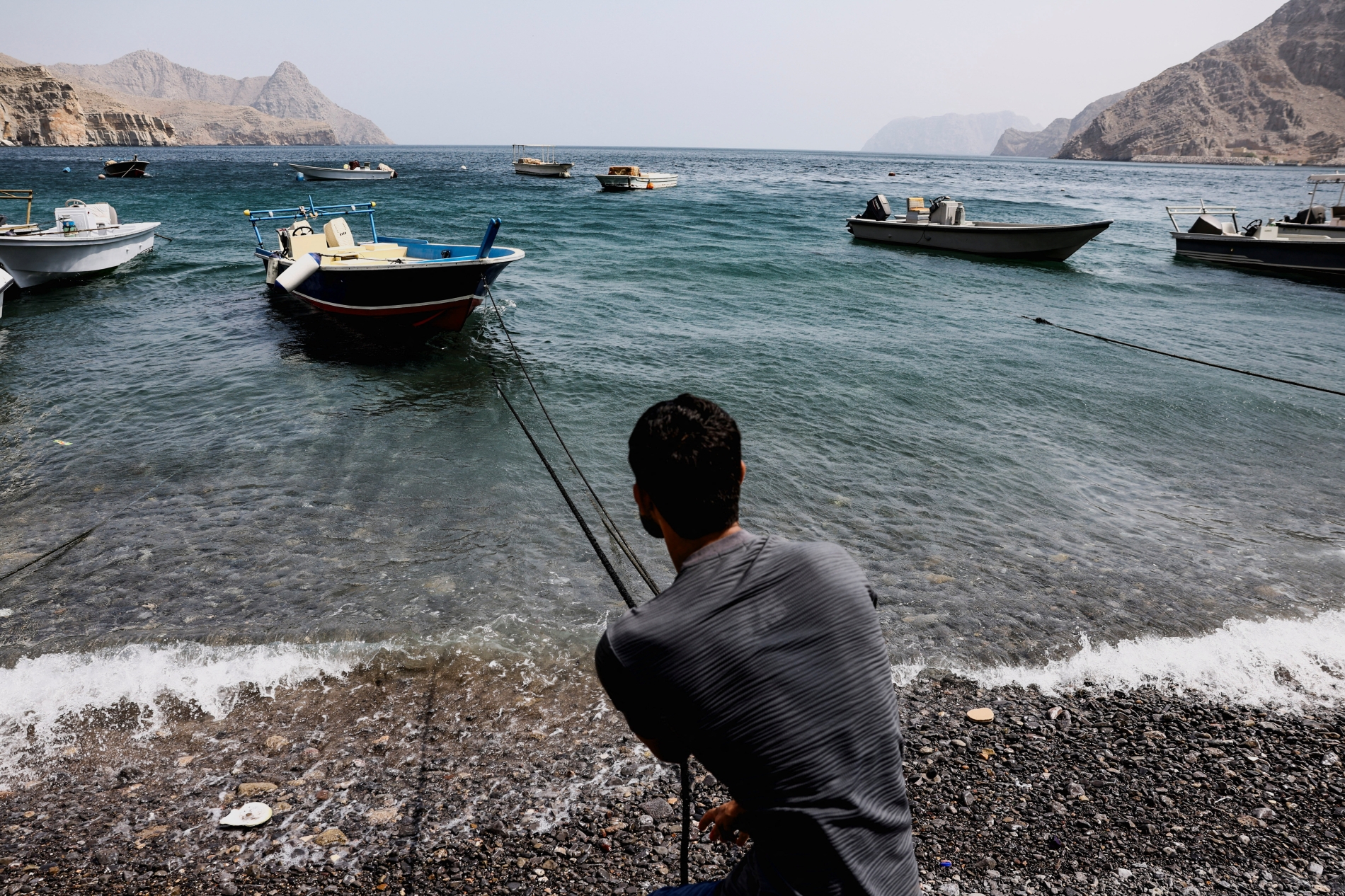 الرجل نفسه يرسو بقاربه في كمزار، وهي قرية في مسندم تُطل على مضيق هرمز وتُعرف بلغتها الخاصة «الكمزارية» التي يتحدث بها سكانها، في عُمان، ٢٧ أغسطس ٢٠٢٥