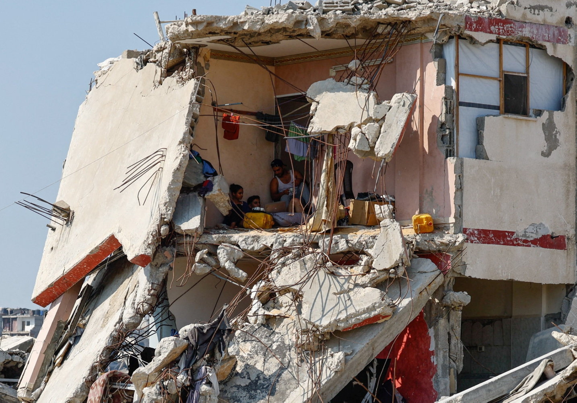 فلسطينيون يجلسون داخل منزل تضرر خلال الحرب، محاطين بمبانٍ مدمرة، في مدينة غزة، 15 أغسطس محمود عيسى- رويترز
