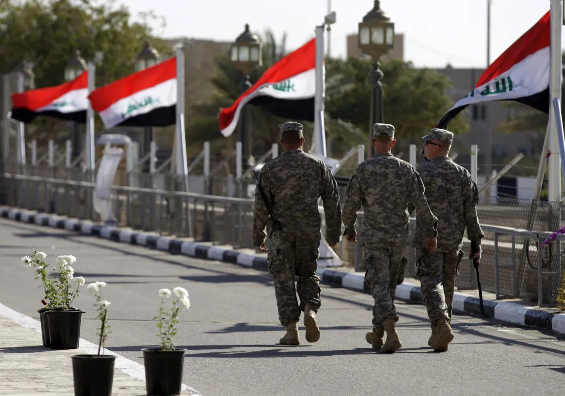 جنود أميركيون يسيرون بجوار الأعلام العراقية أثناء مغادرتهم قصر الفاو في معسكر النصر بعد إحدى الاحتفالات العديدة المخطط لها لإحياء ذكرى انتهاء الوجود العسكري الأميركي في العراق، في بغداد، 1 ديسمبر 2011 أ ف ب