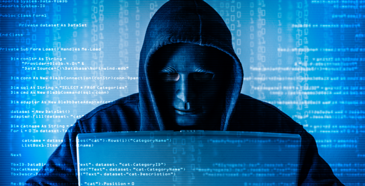 The abstract image of the hacker wearing a mask and using a laptop in the empty white room overlay with source code hologram. (Getty)