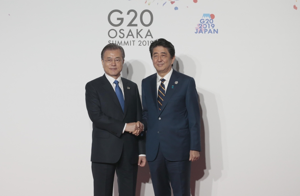 President of South Korea Moon Jae-in (L) is welcomed by Japanese Prime Minister Shinzo Abe (R) on the first day of the G20 summit in Osaka, Japan on June 28, 2019. (Getty)