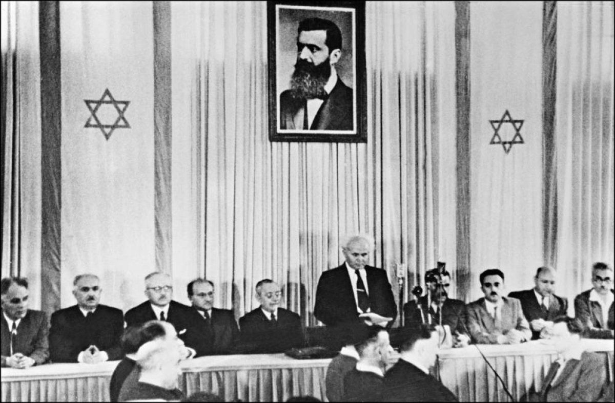 On May 14, 1948, Israeli Prime Minister David Ben-Gurion (standing under a huge portrait of Theodor Herzl, the founder of political Zionism, proclaims the establishment of Israel.