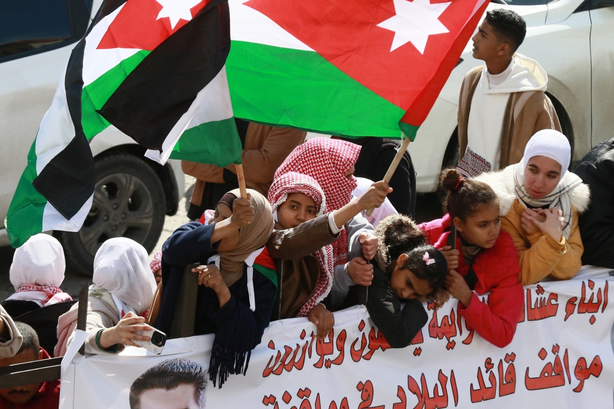 People wave flags as they gather along the road leading to Amman&#039;s Marka Airport to welcome King Abdullah II upon his return on February 13, 2025, from Washington, DC, where he met with US President Donald Trump.
