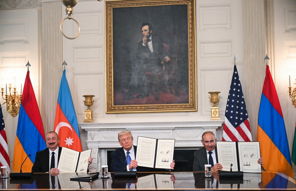 US President Donald Trump (C), Azerbaijani President Ilham Aliyev (L) and Armenian Prime Minister Nikol Pashinyan display the agreement they signed in the State Dining Room of the White House in Washington, DC, on August 8, 2025.