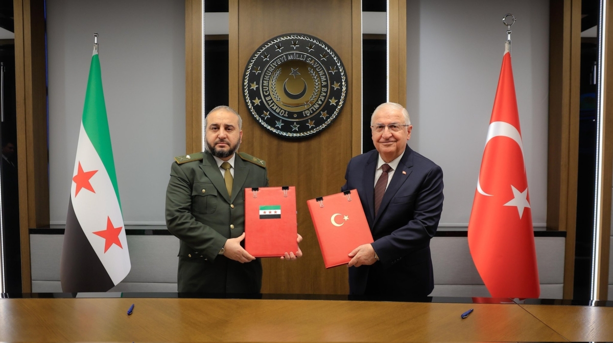 Syrian Defence Minister Murhaf Abu Qasra and Turkish Defence Minister Yaşar Güler hold up an MOU on security cooperation in Ankara on August 13, 2025.