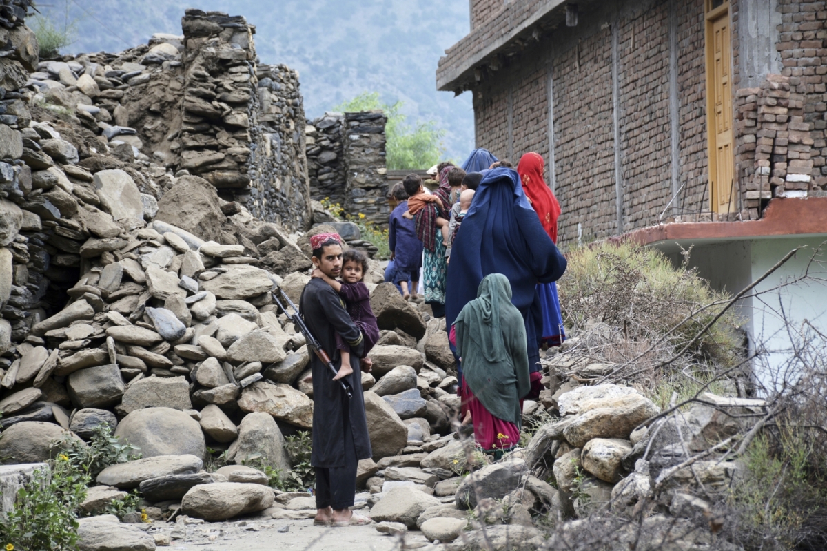 Local residents walk past a house destroyed by an earthquake that killed nearly 1,000 people and devastated villages in eastern Afghanistan, on September 1, 2025.