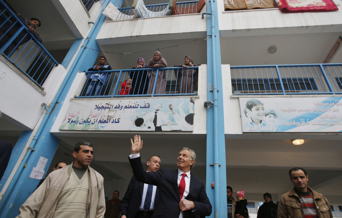 Middle East Quartet envoy Tony Blair (C) waves as he leaves a UN-run school sheltering Palestinians, whose houses were destroyed by Israeli airstrikes during the 2014 war, in Gaza City on February 15, 2015.