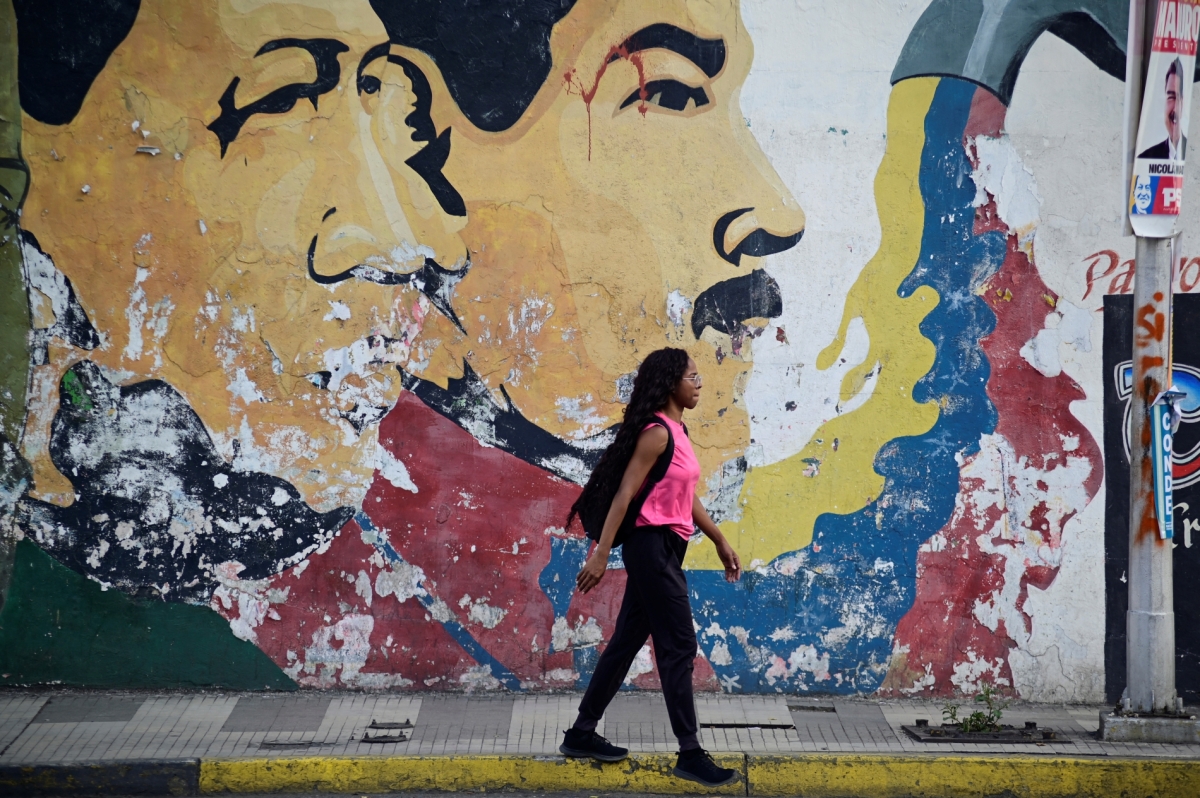 A woman walks past a mural depicting late former Venezuelan President Hugo Chavez and Venezuelan President Nicolas Maduro in Caracas, Venezuela July 27, 2024. 