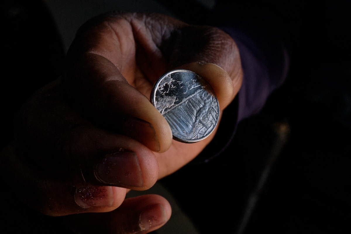 A customer receives the new $5 ZiG, short for Zimbabwe Gold, coins as change from a cashier in a leading supermarket in Harare on April 30, 2024.