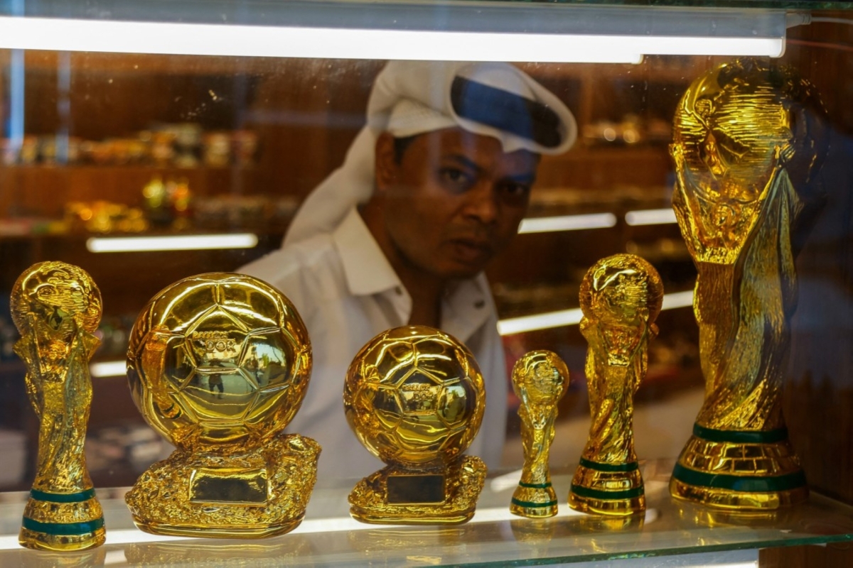 A shopkeeper looks out through a window displaying replicas of football trophies at a gift shop in Souq Waqif bazaar in Doha on July 24, 2025. 