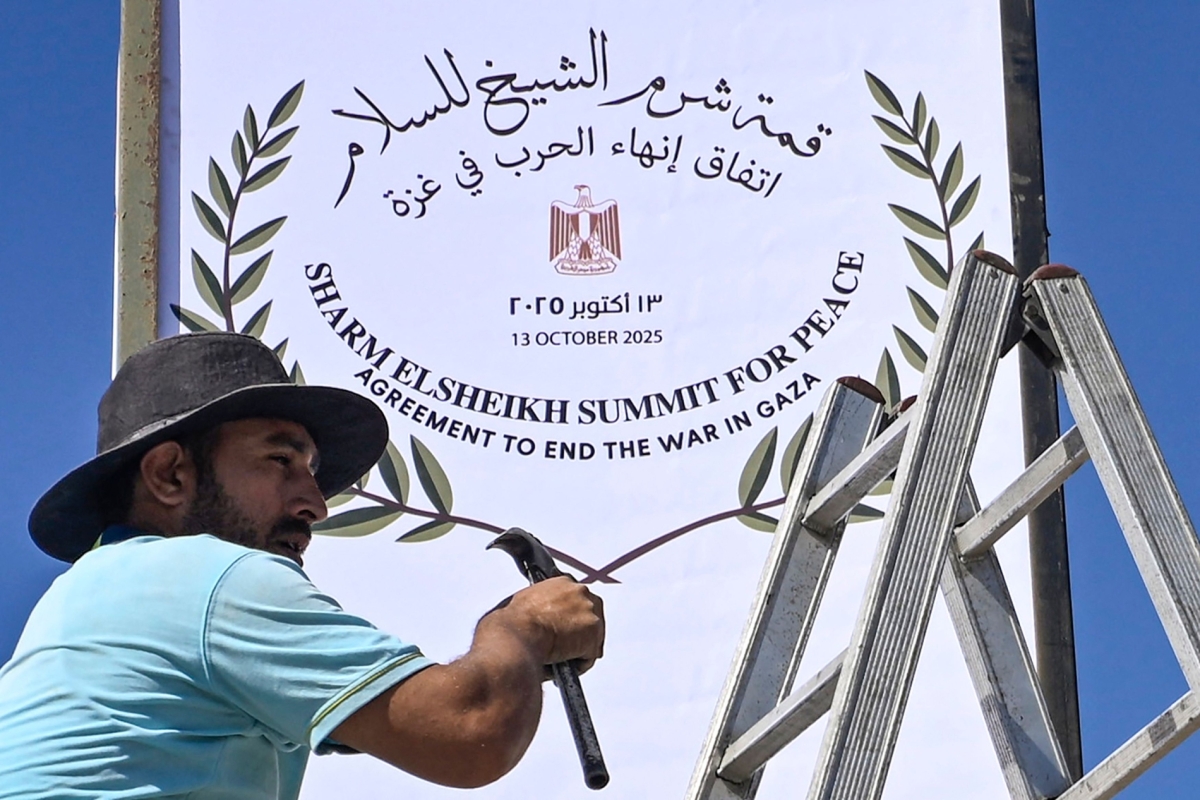 A municipal worker fixes a sign in Sharm el-Sheikh, as the Egyptian resort town gets ready to host a US-brokered Gaza peace summit, on October 12, 2025.