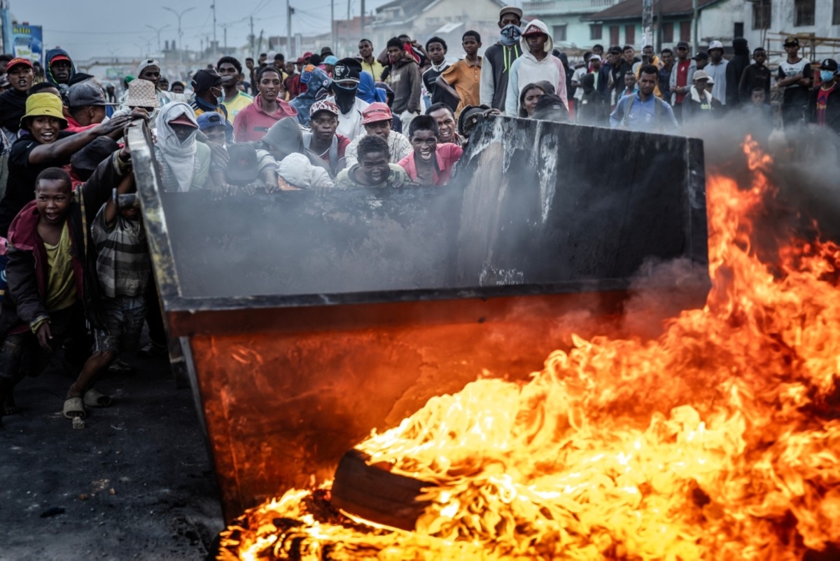 Protesters push a metal container to use as a barricade during clashes with security forces amid a strike calling for constitutional reforms and the resignation of President Andry Rajoelina in Antananarivo, on October 9, 2025.