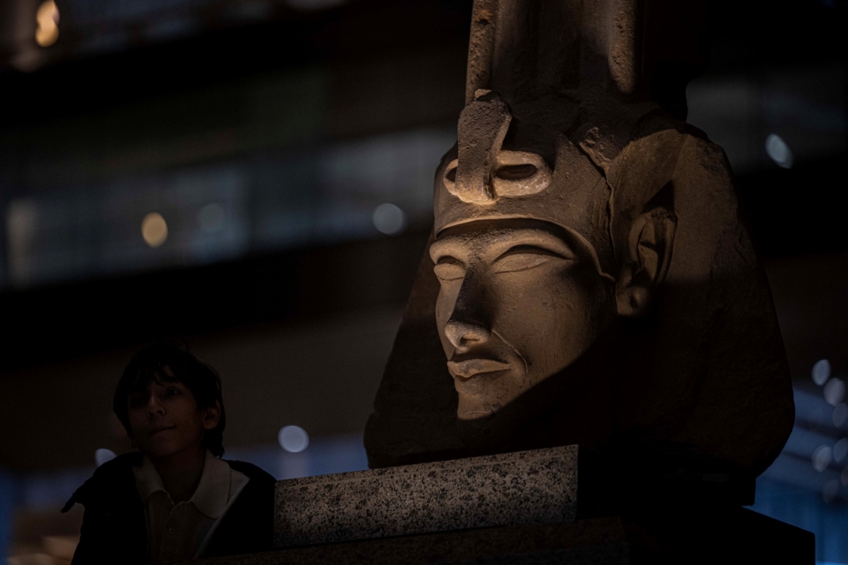 A visitor walks near a bust of the ancient Egyptian King Akhenaten while touring the Grand Egyptian Museum, in Giza on the southwestern outskirts of the capital Cairo on 7 February 2025.