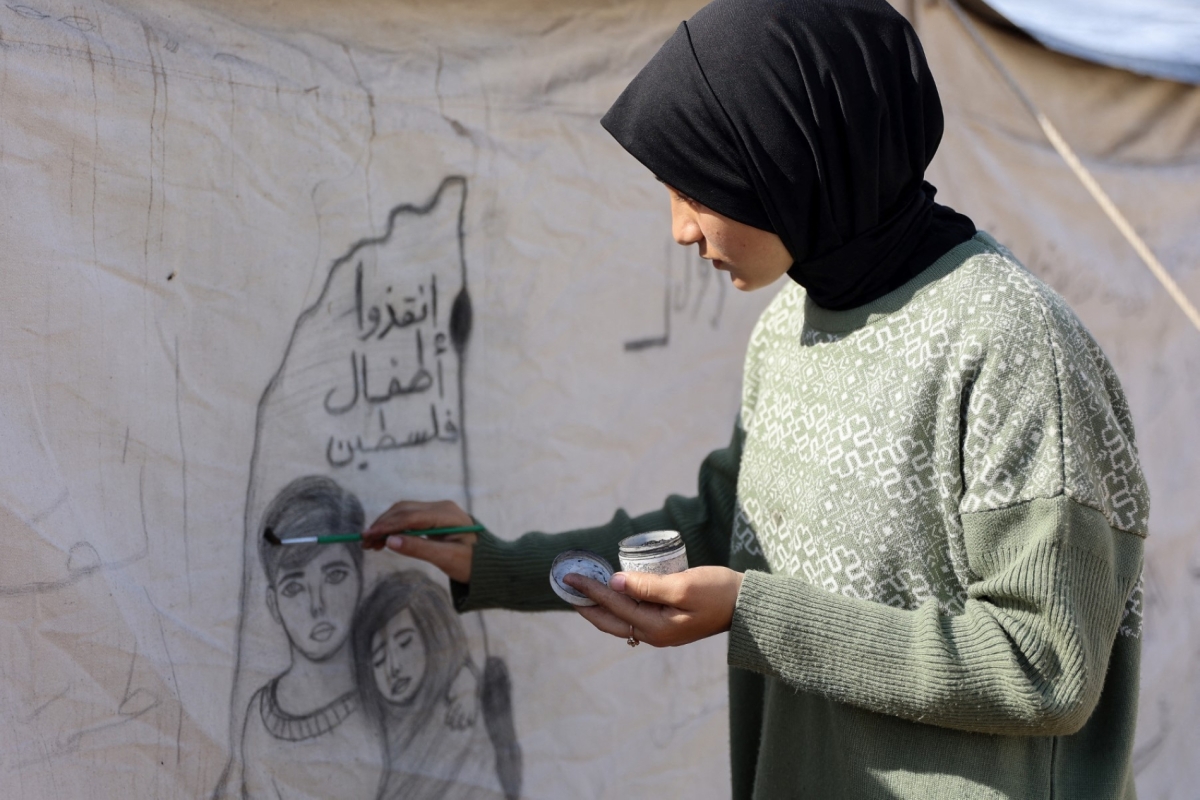 Israa Saada (17 years old) draws on a tent in a displaced persons camp in Gaza.