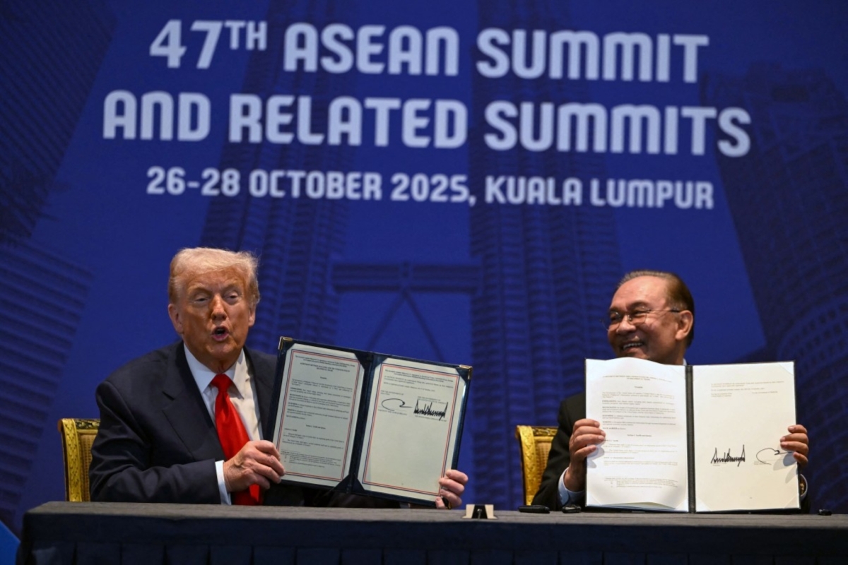 US President Donald Trump (L) and Malaysia's Prime Minister Anwar Ibrahim (R) hold up signed documents on a trade deal during a bilateral meeting on the sidelines of the 47th ASEAN Summit in Kuala Lumpur on 26 October 2025. 