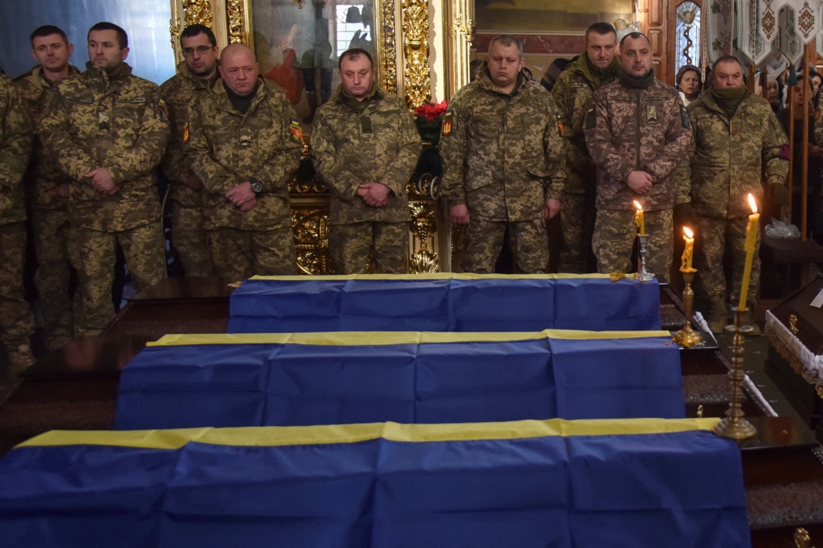 Ukrainian soldiers stand next to the bodies of their unidentified brothers-in-arms who died fighting Russian troops in Donetsk in 2022-2023. Their bodies were returned during a swap in November 2025.