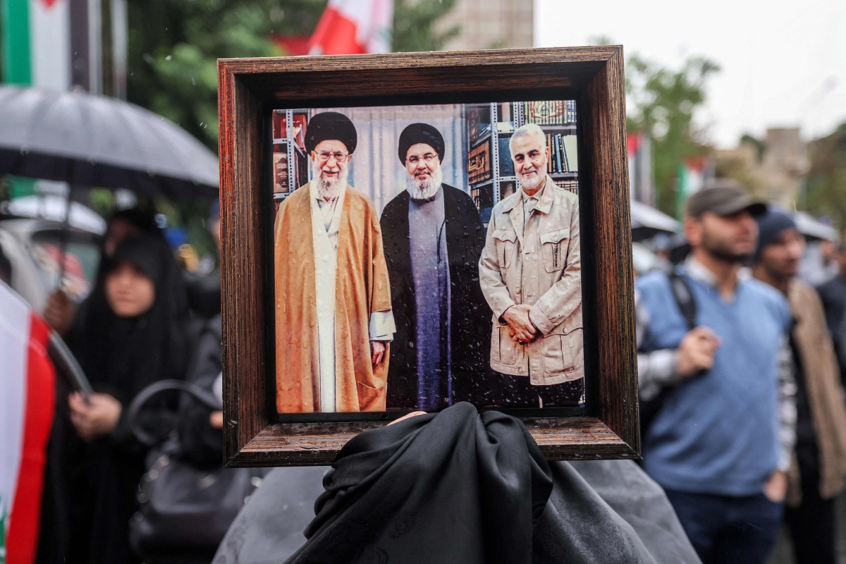 An Iranian holds a picture of Supreme Leader Ali Khamenei; Hezbollah leader Hassan Nasrallah, killed by an Israeli air strike on September 27, 2024; and Iran Quds Force Commander Qasem Soleimani, killed by the US in January 2020.
