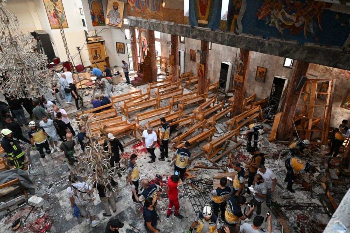 People and rescuers inspect the damage at the site of a reported suicide attack at the Saint Elias church in Damascus' Dwelaa area on 22 June 2025. 
