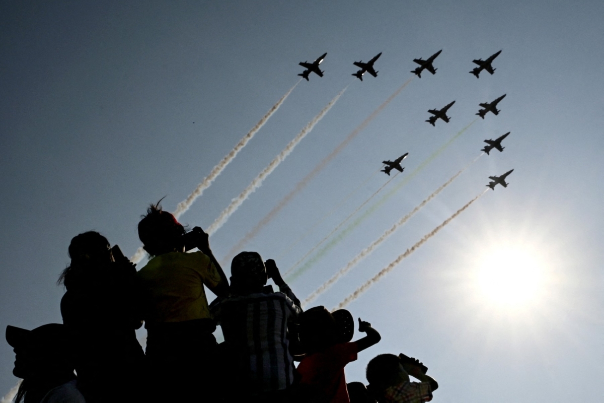 Children watch the Indian Air Force (IAF) Surya Kiran aerobatics team performing during Aero India 2025, a military aviation exhibition at the Yelahanka Air Force Station in Bengaluru on 13 February 2025. 