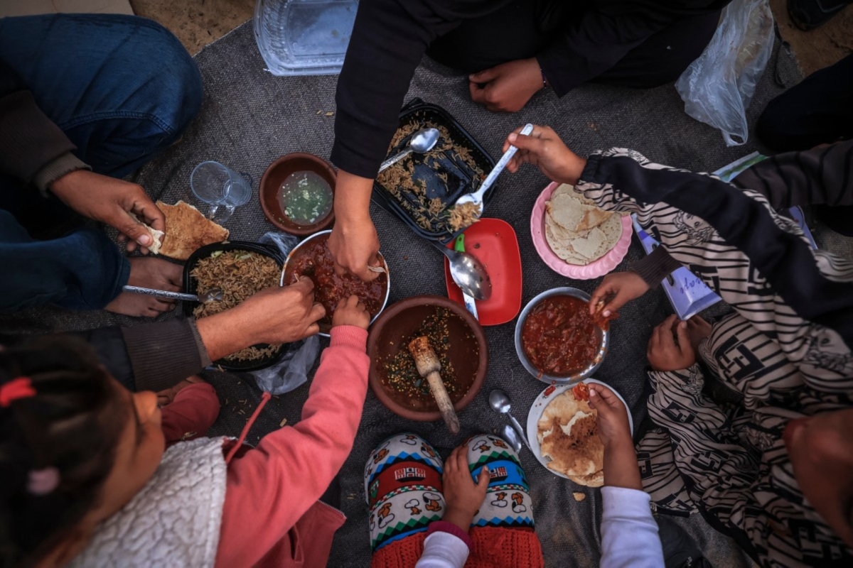 The displaced Palestinian Abu Mustafa family sits together as they break the dawn-to-dusk Ramadan fast during Iftar in the Nuseirat refugee camp in the central Gaza Strip on 26 February 2026.