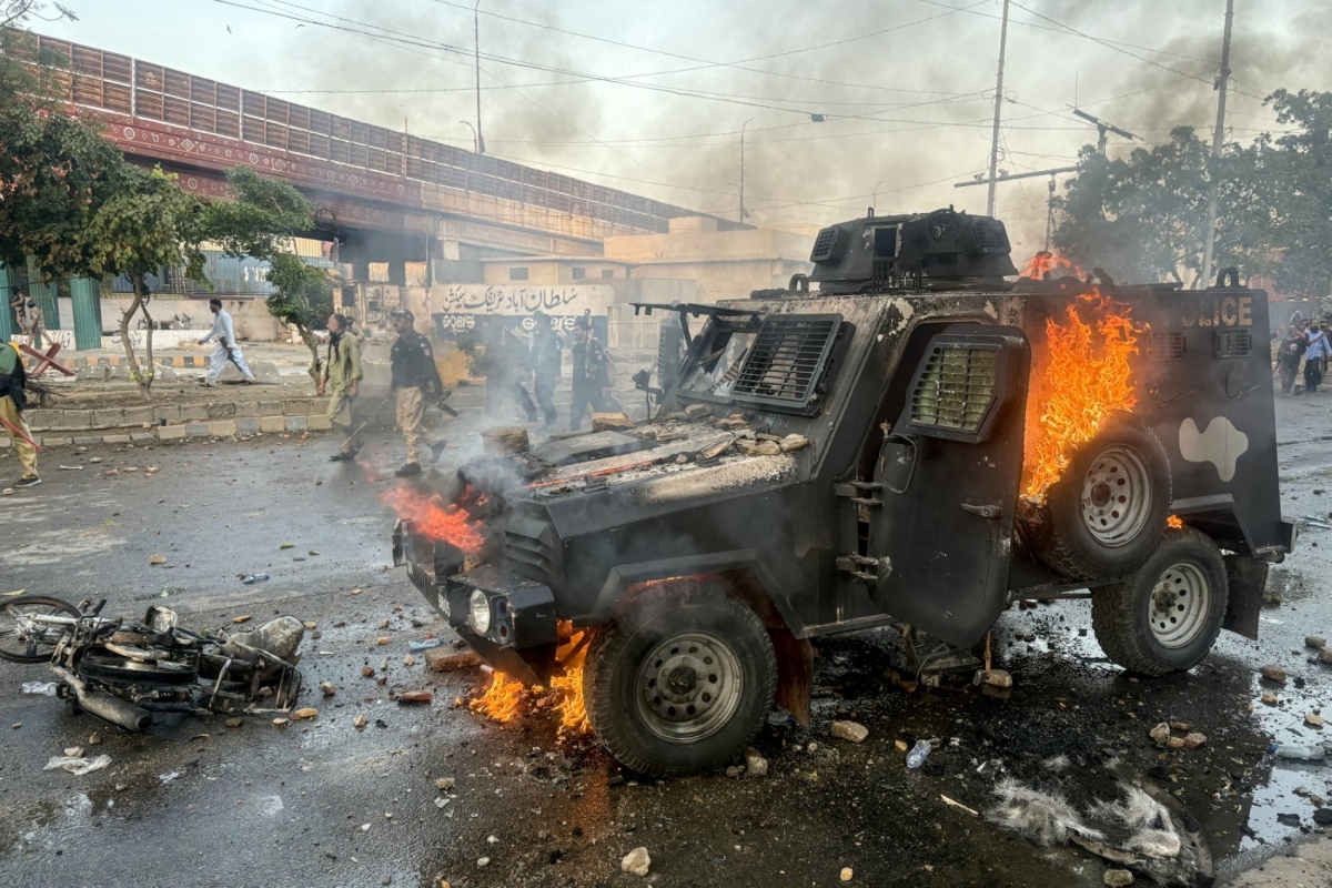 Police walk past a burning armoured vehicle set on fire by protestors outside the US consulate in Karachi, Pakistan on March 1, 2026 after the killing of Iran's Supreme Leader.