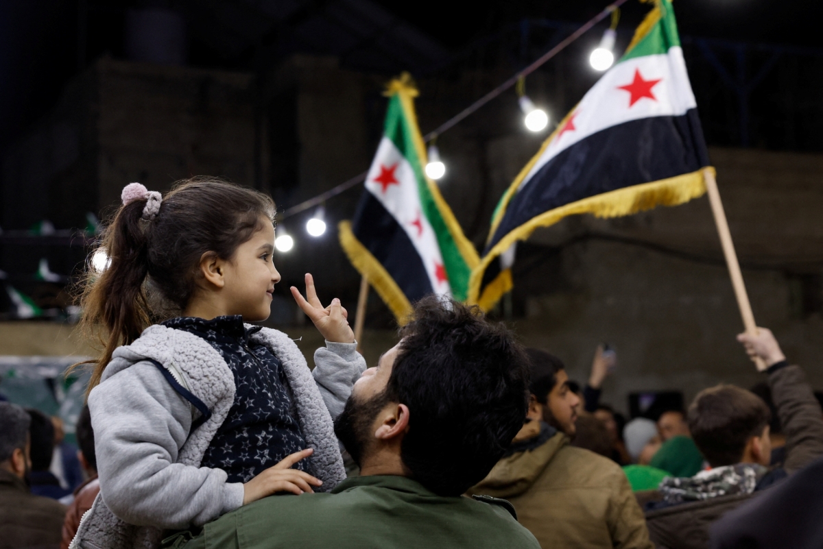 A girl shows a peace sign, as Syrians gather to mark the anniversary of the 2011 uprising against the ousted President Bashar al-Assad in Damascus, Syria, on 15 March 2026.