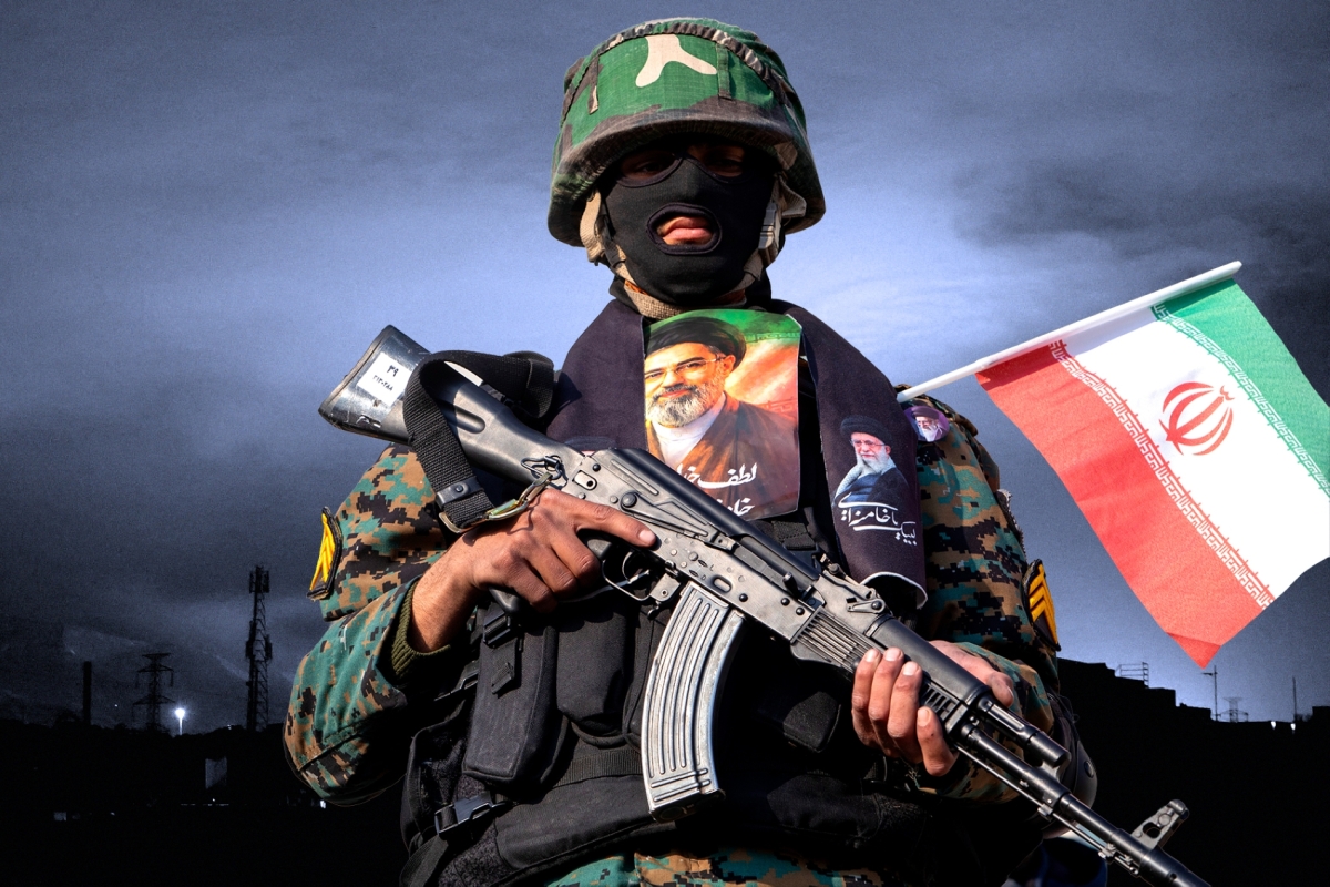 A member of the security forces, holding a picture of Iran's new Supreme Leader Mojtaba Khamenei, observes protesters as they gather for a rally in support of the new Supreme Leader in Enghelab Square in Tehran, on 9 March 2026.