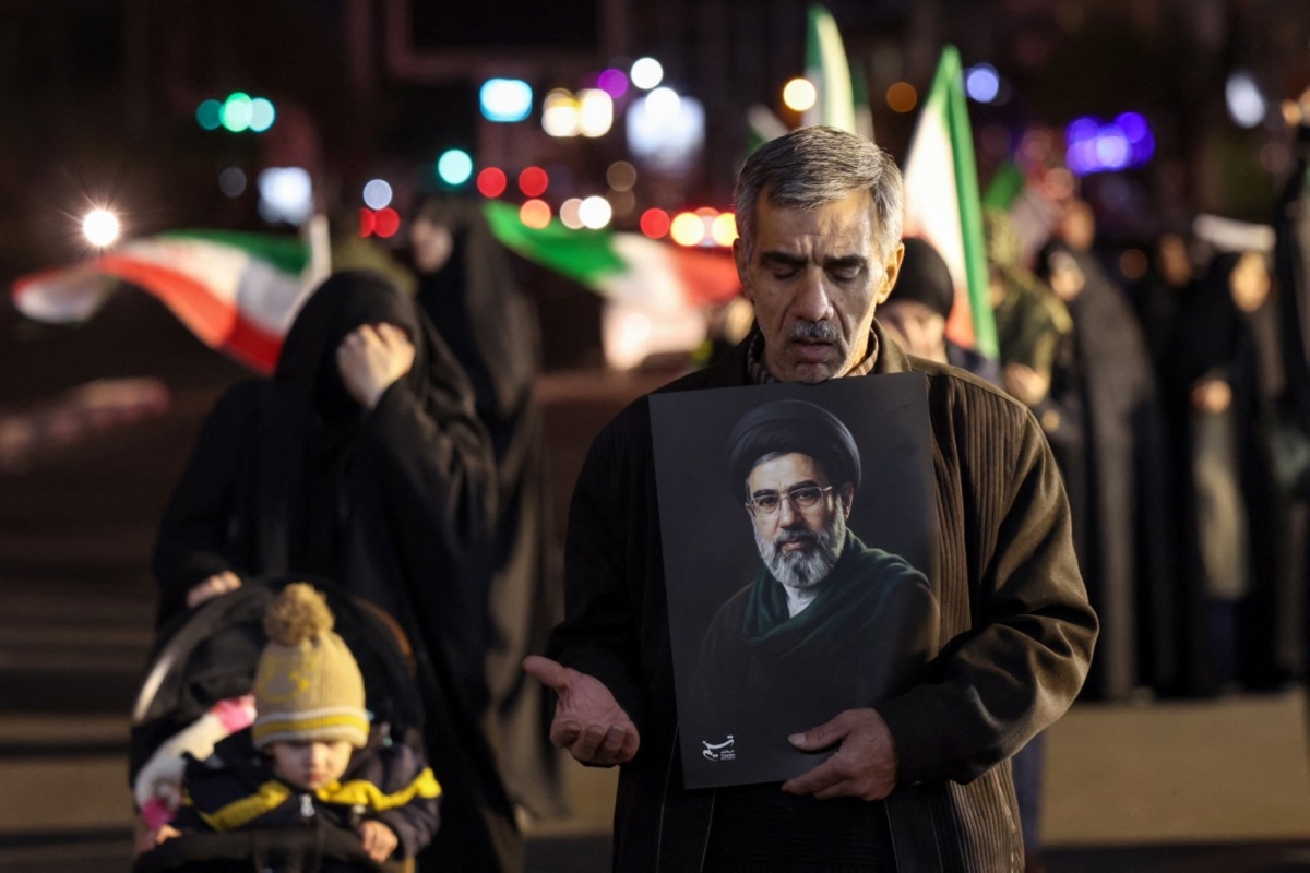 A man reacts as he holds a portrait of Iran's supreme leader Mojtaba Khamenei as people march in support of the Iranian armed forces in central Tehran on 25 March 2026.