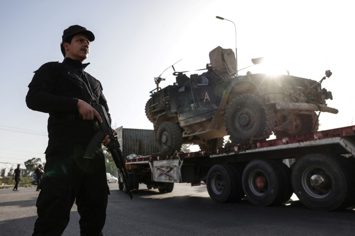 Syrian security stands guard as a convoy of US military equipment is transported along the Damascus–Amman highway as the US withdraws from its bases in Syria on 16 April, 2026.