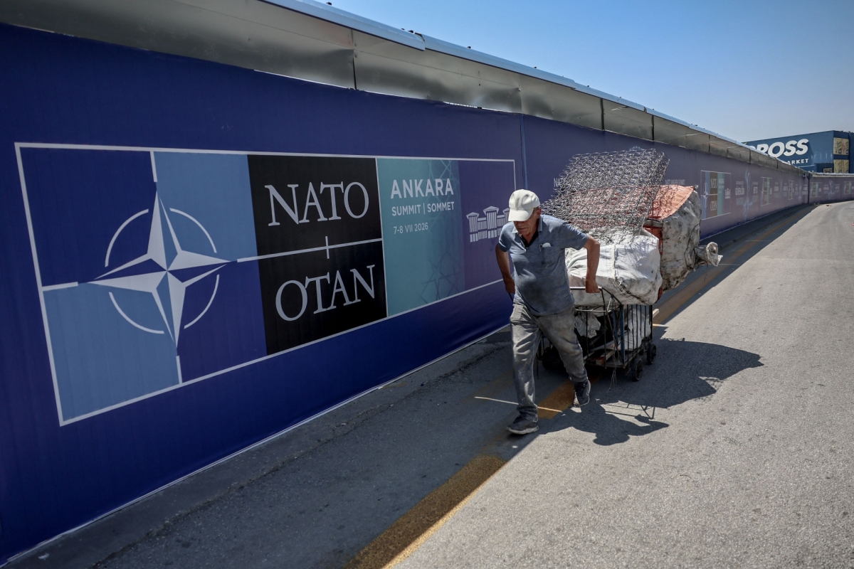 A paper collector pulls his handcart past billboards lining the boulevard along the protocol route ahead of the NATO Summit in Ankara on 2 July 2026.