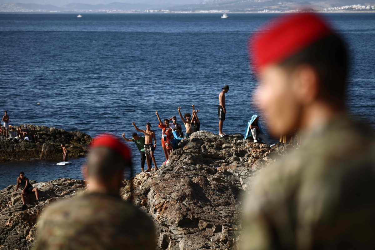 Members of the Spanish Army's 'Regulares' infantry forces watch a group of migrants near the border post of the Spanish enclave of Ceuta on August 2, 2026.