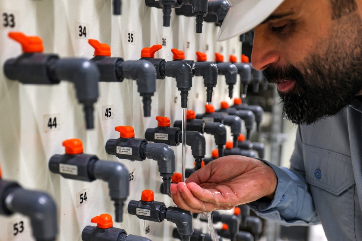The general manager of the Ras al-Khair water desalination plant inspects drinking water from a tap at the facility in eastern Saudi Arabia on 30 March 2023.