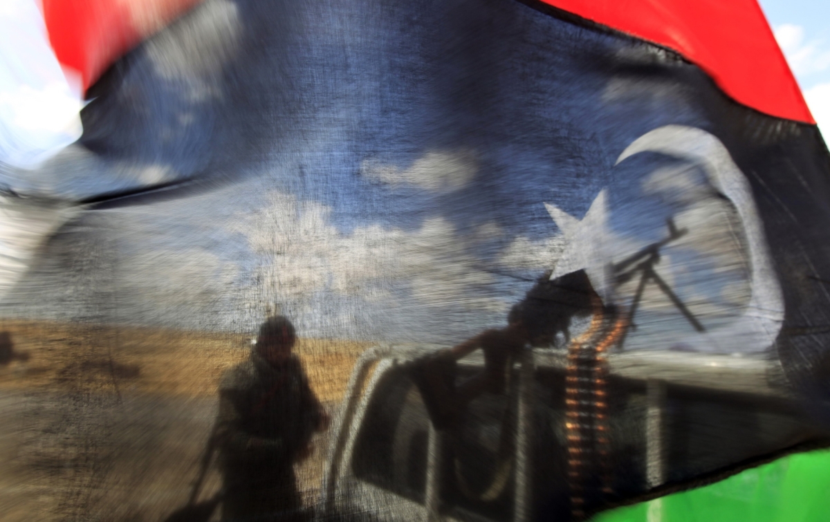 A rebel fighter seen behind a Kingdom of Libya flag near the front line along the western entrance gate of Ajdabiyah, on 18 April 2011.