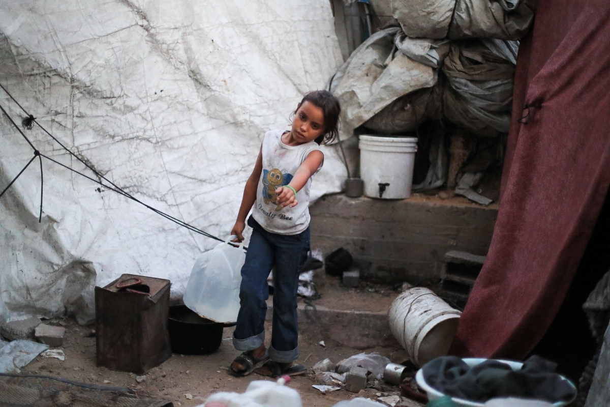 A Palestinian girl carries a container of water at a makeshift tent camp on the premises of the Islamic University in Gaza City, on 3 October 2026. 