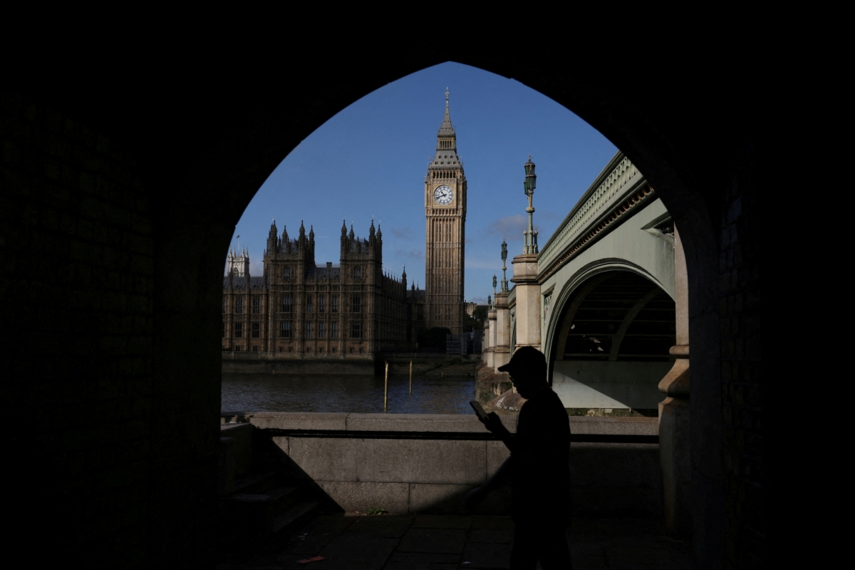 A man looks at his phone in view of the Palace of Westminster in London, Britain, on 22 September 2023. 