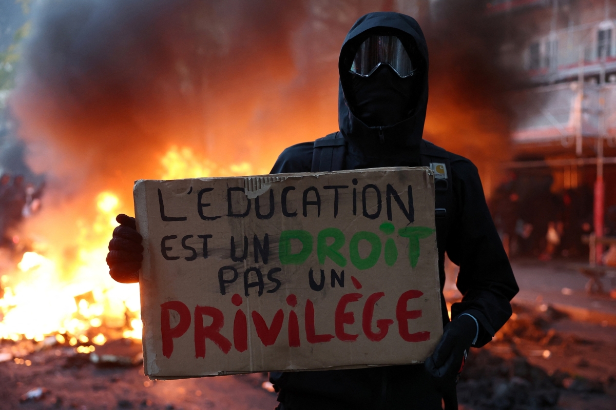 A masked protester holds a placard reading "Education is a right, not a privilege" as part of nationwide protests called by the "Yellow Vests" movement demanding better school conditions in France on 17 October 2026.   