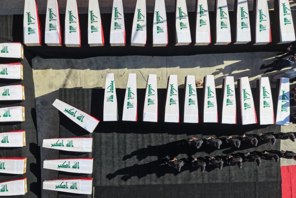 Security forces stand next to coffins lined up during the funeral ceremony of 47 victims killed by the Islamic State (IS) group during its capture of the city of Mosul in 2014, and whose remains were later found on 20 October 2026.