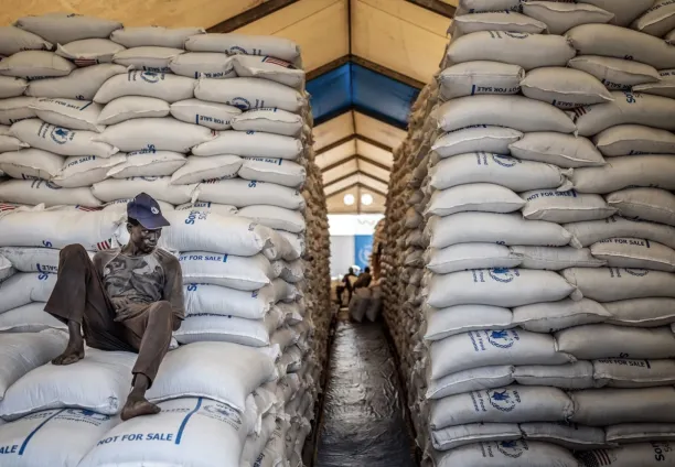 عامل يجلس فوق أكياس من المواد الغذائية داخل عنبر في مستودع تابع لبرنامج الأغذية العالمي في مدينة بور، جنوب السودان، 13 فبراير