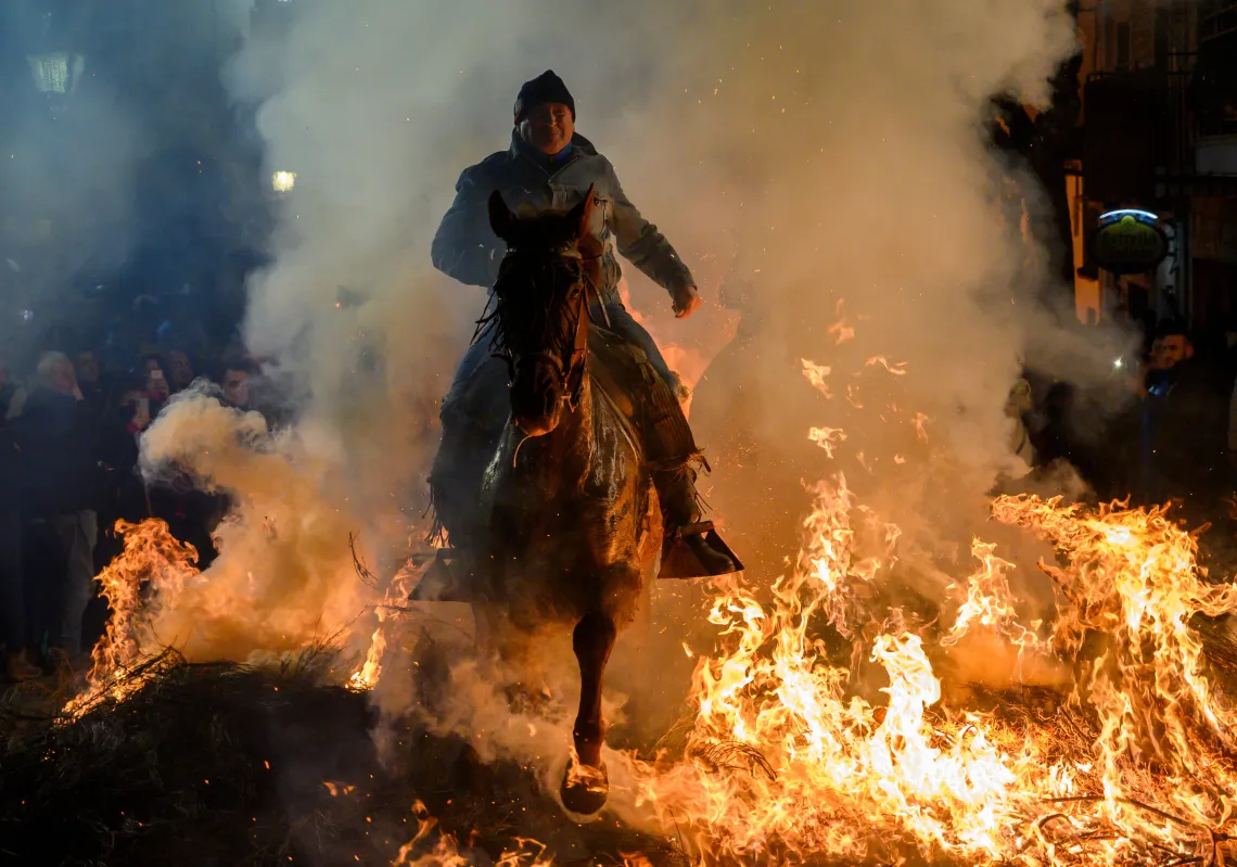 A man rides a horse through a bonfire during the traditional ritual in honor of San Antonio Abad (Saint Anthony the Abbot), patron saint of domestic animals. This tradition known as Las Luminarias, is meant to purify the animals with the smoke of the bonfires and protect them for the year to come. (Getty)