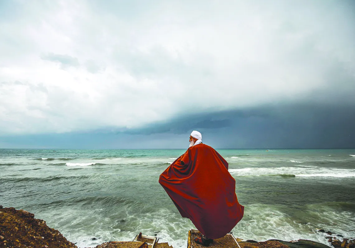 A Palestinian man stands on a beach during stormy weather by his house at al-Shati camp for Palestinian refugees in Gaza City, on January 20, 2020. (