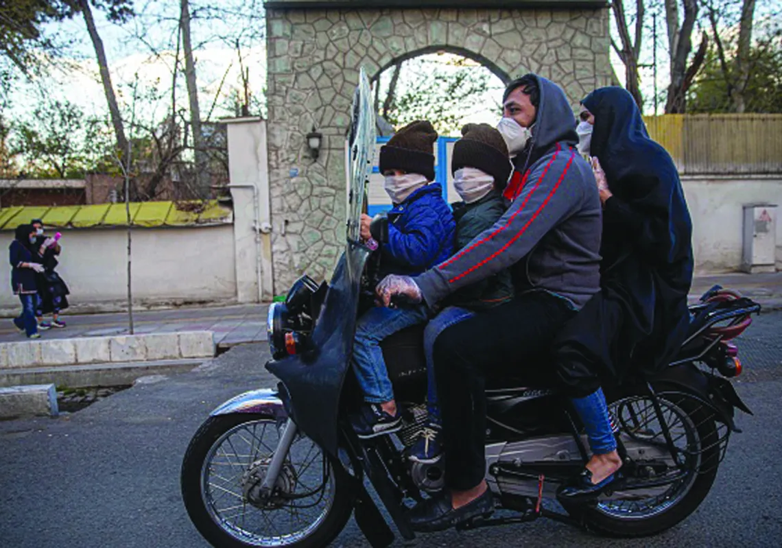 دراجة نارية تقل أسرة ترتدي بأكملها أقنعة خلال مرورها بالمدينة أثناء تفشي وباء فيروس كورونا (غيتي)