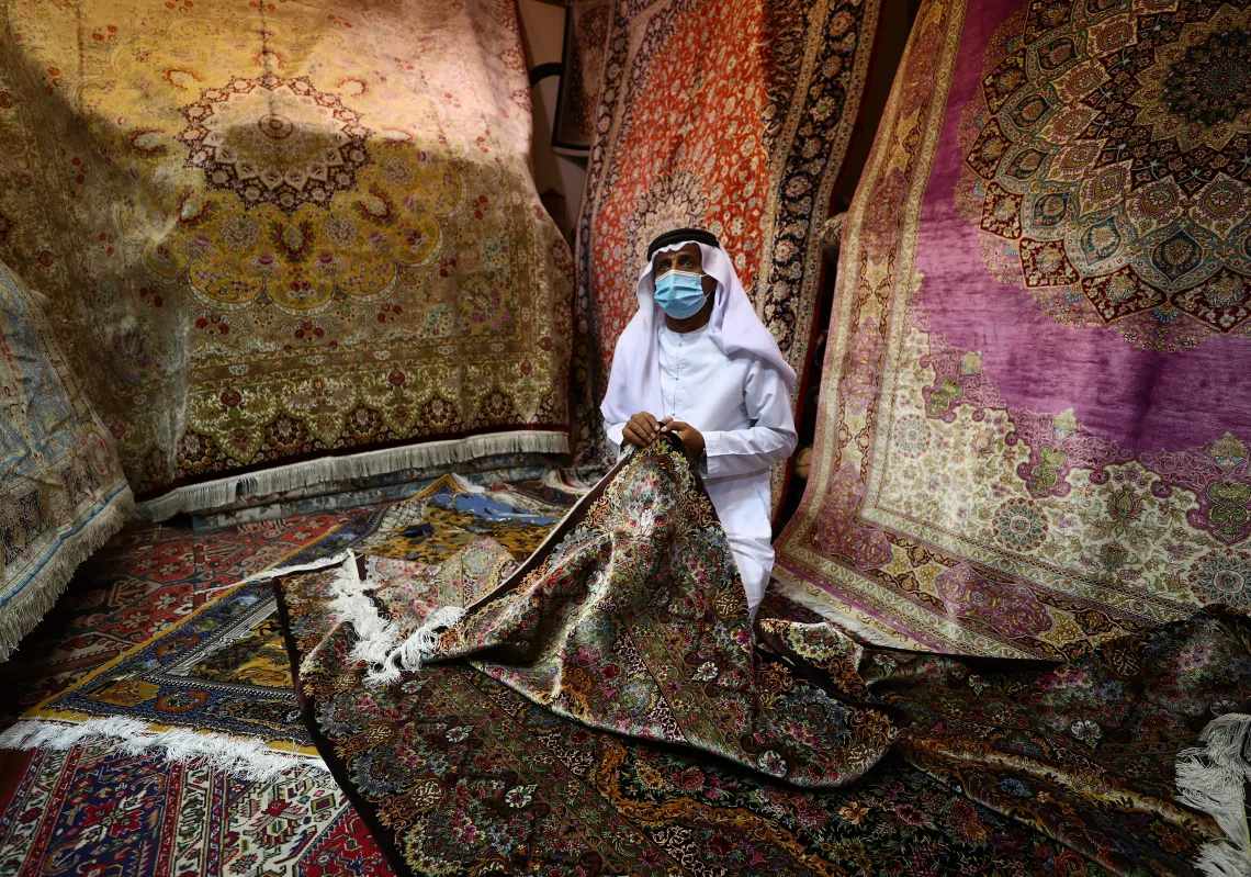 A vendor wearing a mask arranges carpets in his shop at Central Souq on July 09, 2020 in Sharjah, United Arab Emirates.  (Getty)