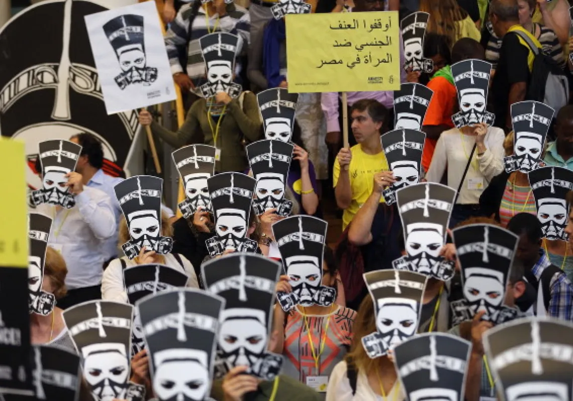 متظاهرون في برلين، ألمانيا، يحملون أقنعة تصور الملكة المصرية نفرتيتي وهي ترتدي قناع غاز احتجاجًا على العنف ضد النساء في مصر (غيتي)