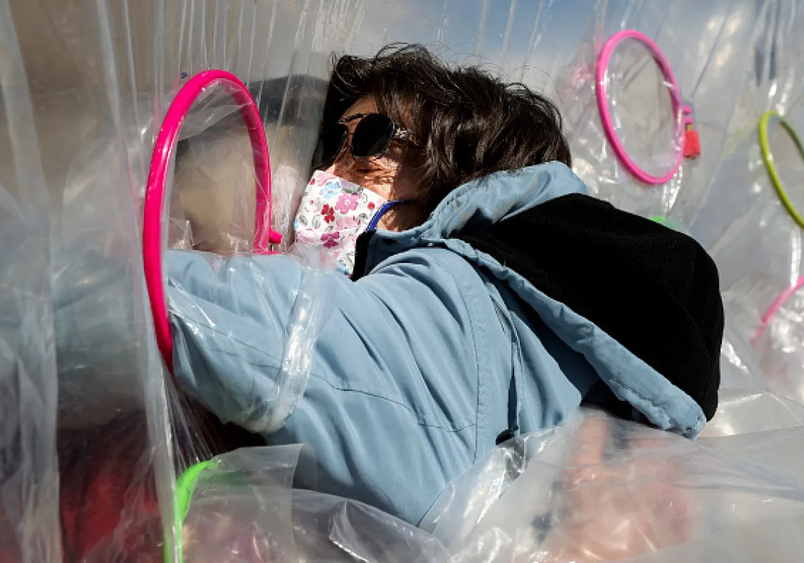 Sandy Kneeland (R) embraces her old friend, Dave Sibila, through a hug tent at the Crossroads Senior Living community on February 26, 2021 in Lakewood, Colorado.(Getty)