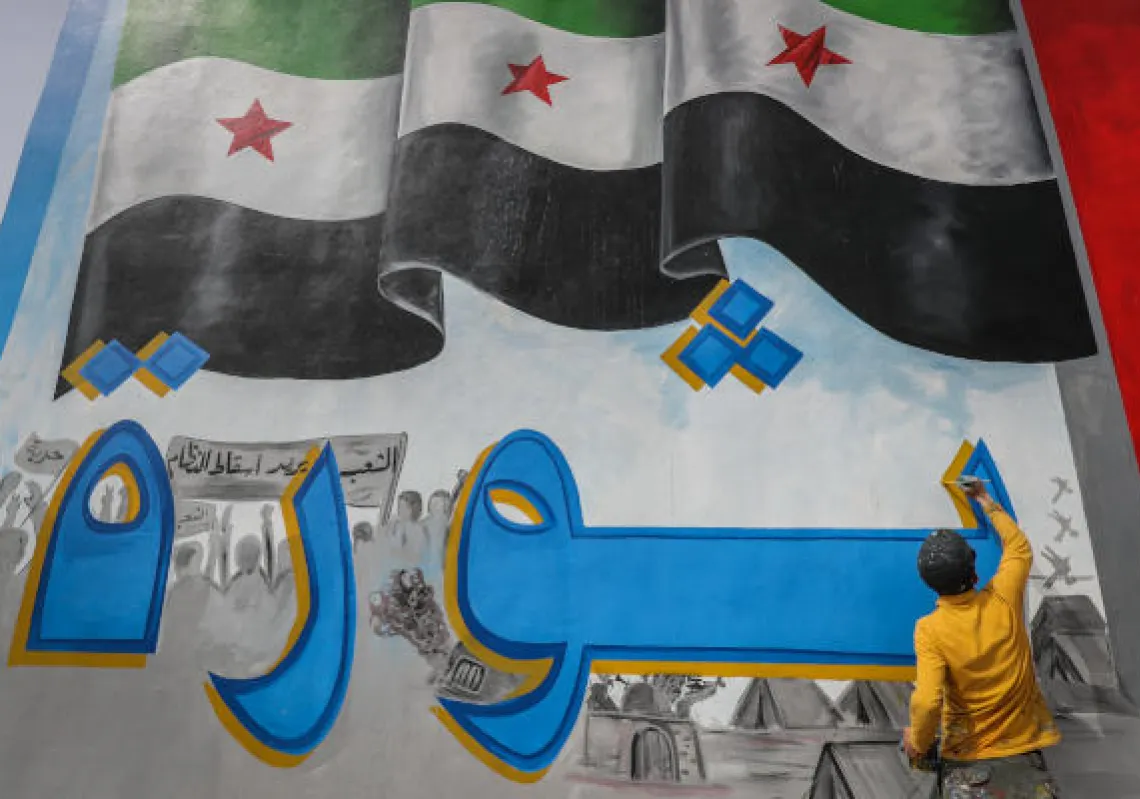 Artist Aziz Al-Asmar and his colleagues paint a mural that comprises the Syrian opposition flag and the word "Revolution" in Arabic, to commemorate 10 years since the start of the Syrian civil war.Syria, Idlib,14 March 2021.(DPA)