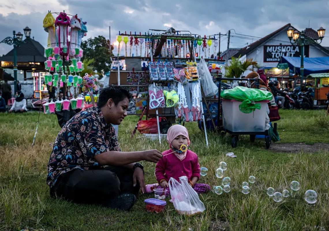 A child with her father plays with soap bubbles as they wait to break their fast during the holy month of Ramadan at the Southern city square known as 'Alun-alun kidul' in Yogyakarta, Indonesia.(Getty) 