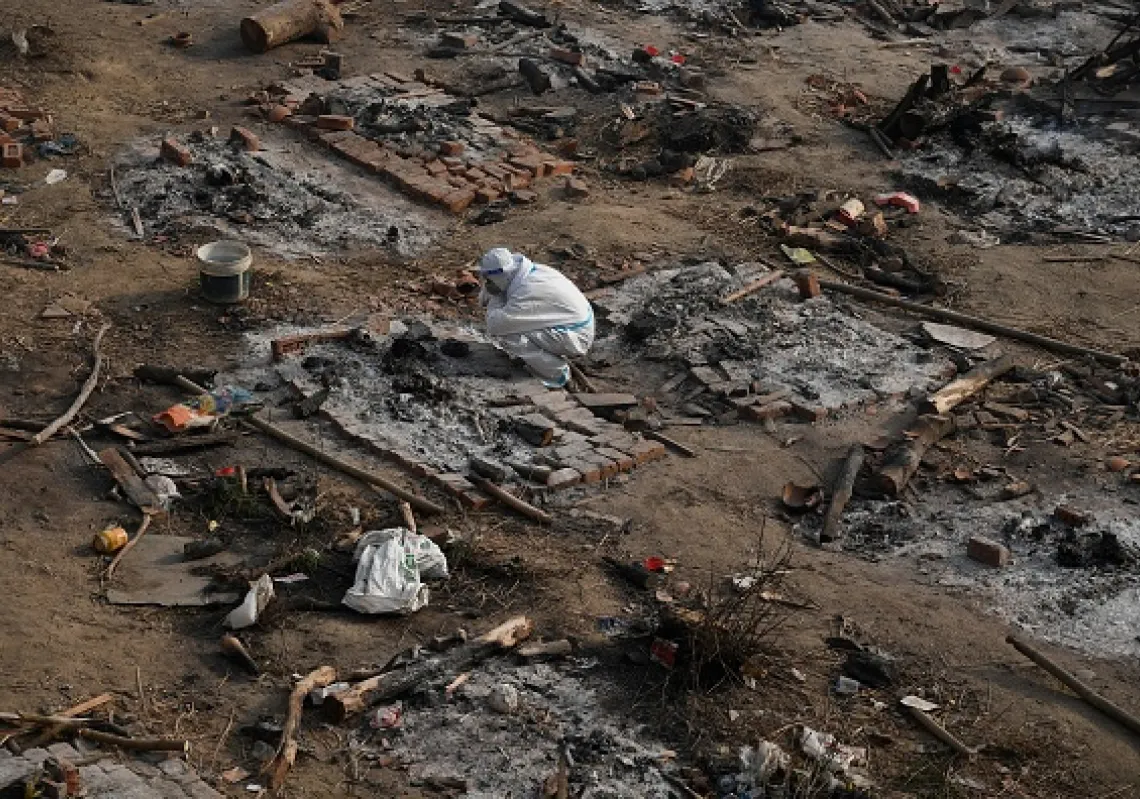 A relative mourns next to the remains of Covid-19 coronavirus victim after a mass cremation at a cremation ground in New Delhi, India.(Getty)
