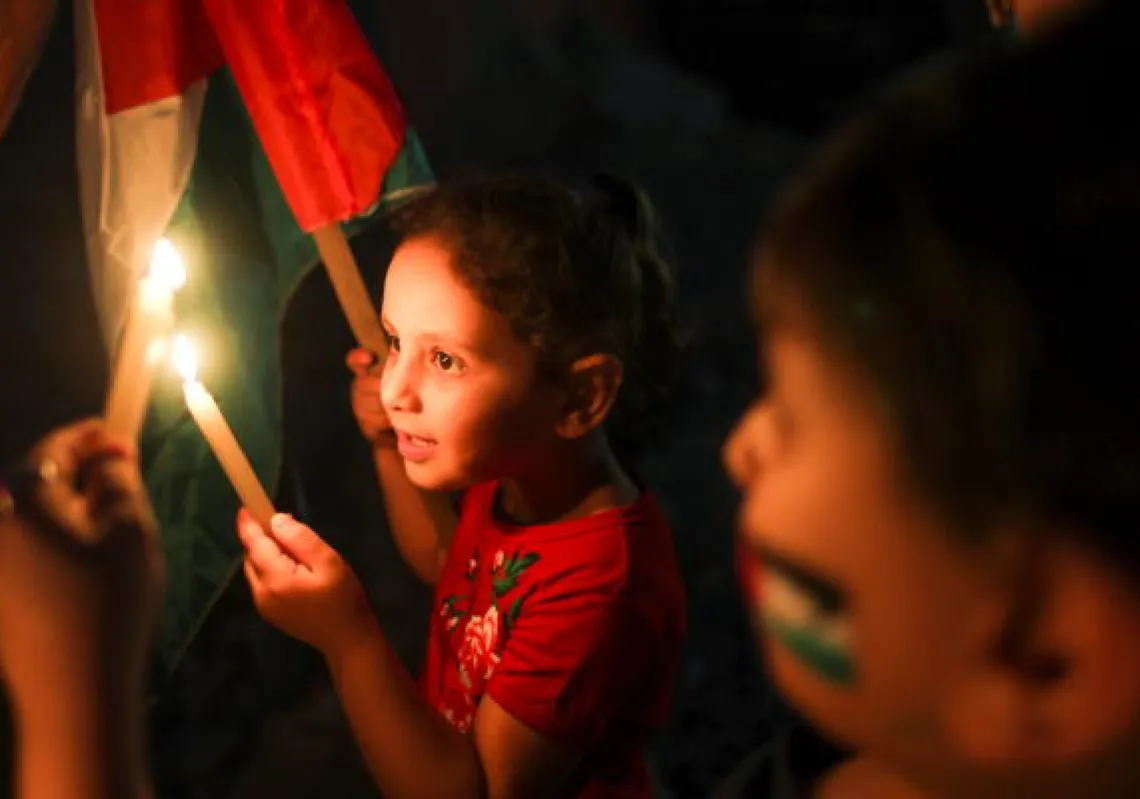 Children hold candles at the site of a house that was destroyed by Israeli air strikes during the Israeli-Palestinian fighting, in Gaza May 23, 2021. (Reuters)