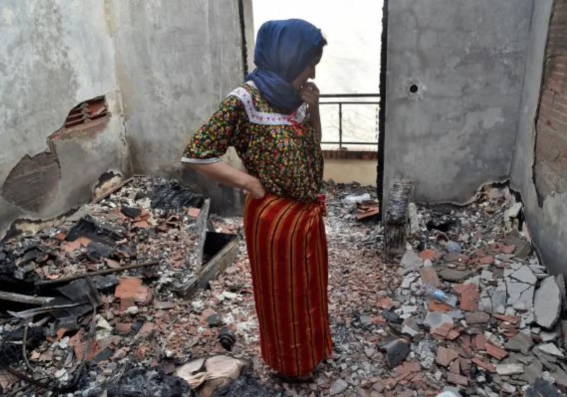 An Algerian woman inspects the damage at her home due to forest fires in the Ait Daoud area of northern Algeria, on August 13, 2021. - Firefighters finally made headway against wildfires that have raged across northern Algeria for days but, as nationwide prayers were held for the dead, anger grew that the country was so ill-prepared. (Photo by Ryad KRAMDI / AFP)