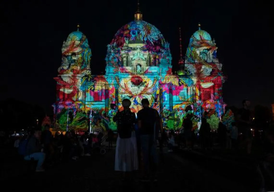 People gather outside the Berlin Cathedral (Berliner Dom) illuminated as part of the yearly Festival of Lights in Berlin on September 3, 2021. (Photo by John MACDOUGALL / AFP)